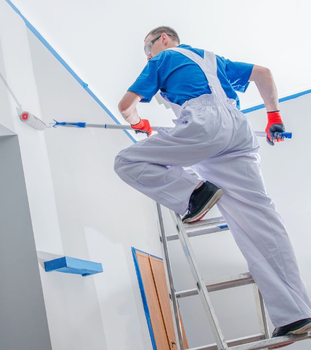 Painter applying paint to an interior wall of a house